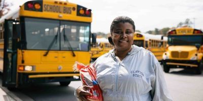 LaQuenda standing in front of yellow school buses.